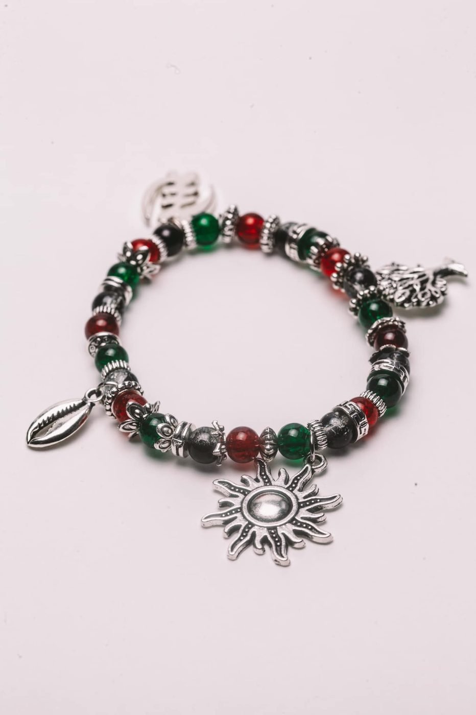 Beaded charm bracelet with silver sun, tree and cowrie charms