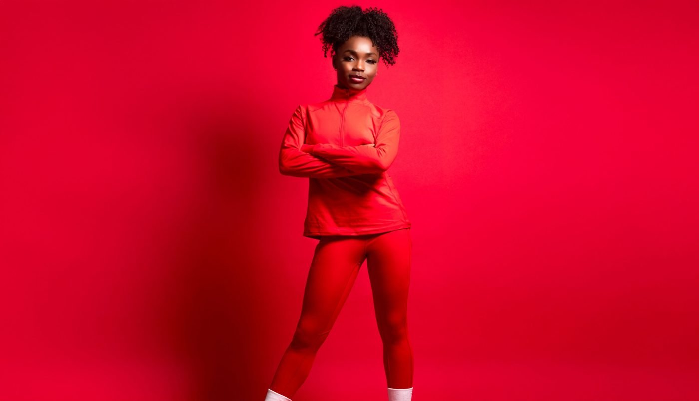Coach in red athletic wear with arms crossed